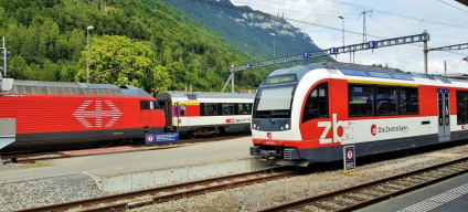 An IC train departs on the left behind a Luzern - Interlaken Express